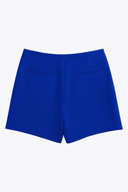 Falda short corto de fit ajustado, cintura alta, cruce frontal con nudo y plisados decorativos frontales. Cierre posterior con cremallera oculta.