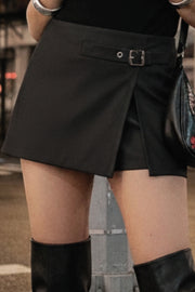 Falda short corto de fit recto, cintura alta, trabilla decorativa con hebilla en contraste, abertura frontal en bajo y cierre lateral con cremallera oculta.