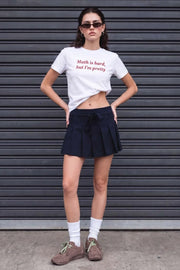 Falda short corto tableado, de corte en a, cintura alta con pretina, trabillas y lazo amarrable del tejido. Detalle de tableado en bajo y cierre lateral con cremallera oculta.