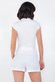 Falda short de fit ajustado, cintura alta, cruce frontal asimétrico, vivos decorativos posteriores y cierre lateral con cremallera oculta.