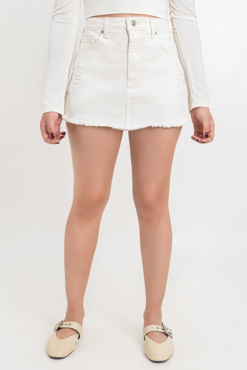 Falda short corto de denim, fit recto , cintura alta con pretina, trabillas, bolsillos delanteros y traseros de parche. Detalle de rotos en bajo, cierre frontal con cremallera oculta y botón en contraste.