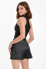 Falda short corto satinado de cintura alta con pretina y trabillas, corte en a, bolsillos delanteros y laterales cargo con cartera. Cierre frontal con broche y cremallera ocultos.