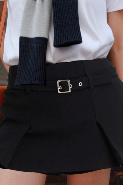 Falda short corto tableado, de cintura media, trabillas y cinturón con hebilla en contraste. Cierre lateral con cremallera oculta.