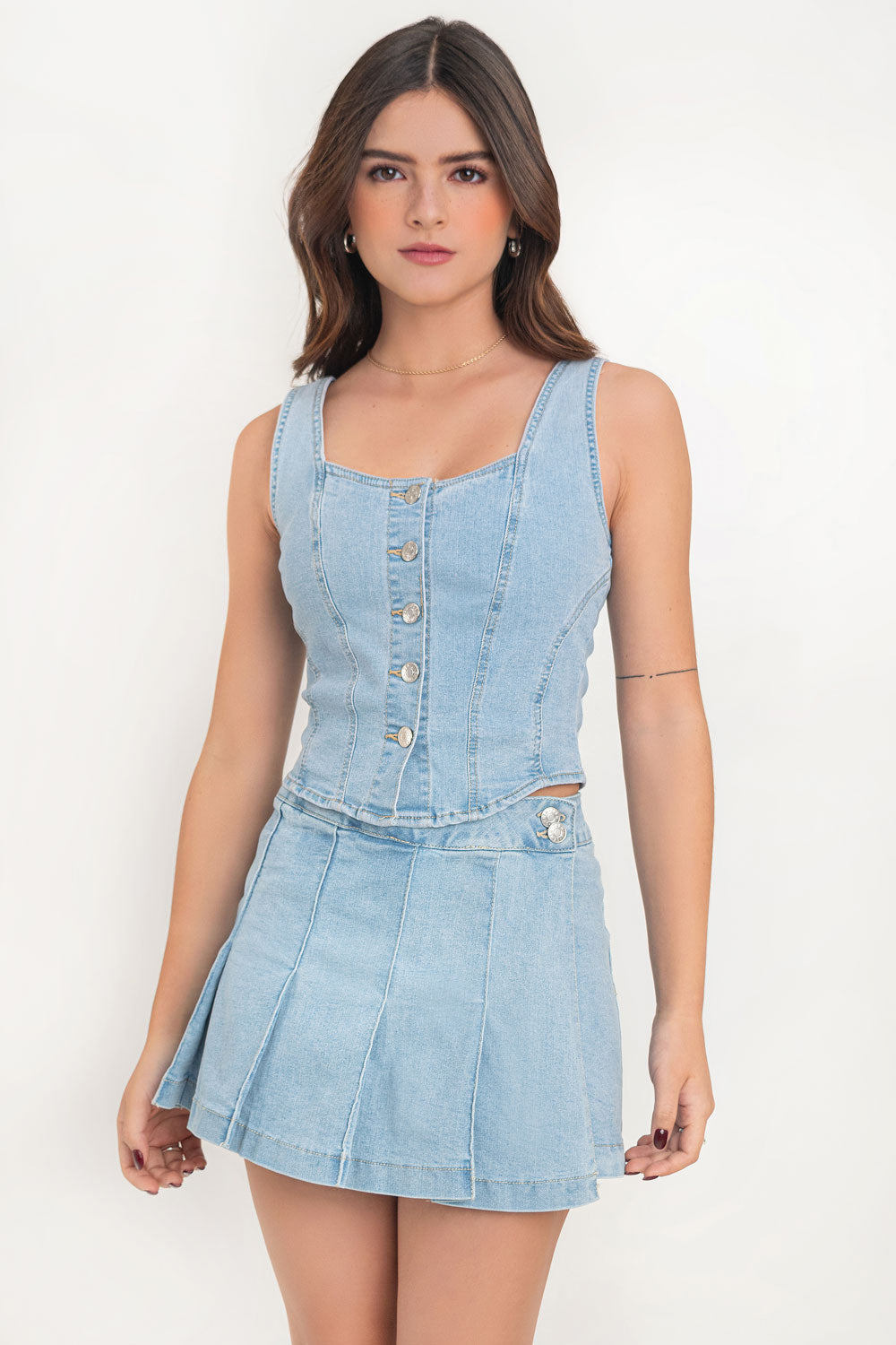 Falda short corto tableado de denim, cintura alta con pretina, corte en a, cruce frontal y cierre lateral con botones en contraste. Detalle de tableado frontal y vivo decorativo posterior.
