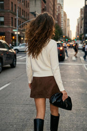 Falda short corto de gamuza, corte en a, cintura alta con pretina, abertura frontal en bajo y cierre lateral con cremallera oculta. Detalle de cinturón decorativo con hebilla en contraste.