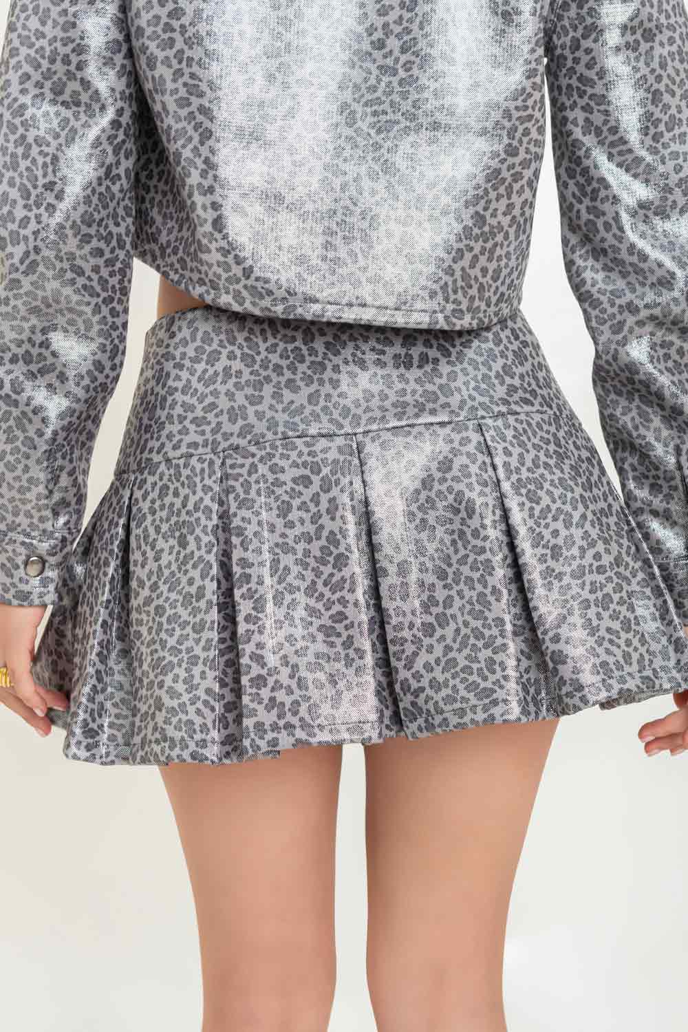 Falda short de estampado animal, cintura alta con pretina ancha, corte en a, tableado en bajo y cierre lateral con cremallera oculta. Detalle de efecto metalizado en tejido.