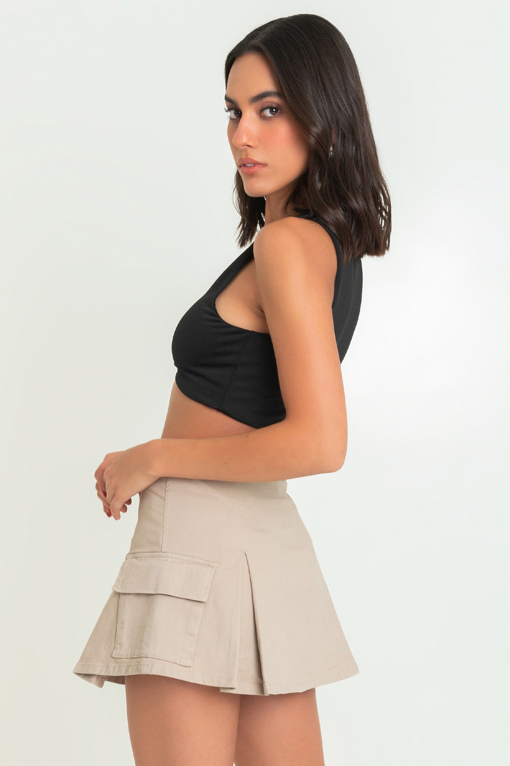Falda short corto cargo, de cintura alta con pretina, corte en a, bolsillos laterales cargo con cartera, tableado frontal y posterior. Cierre frontal con botón en contraste y cremallera oculta.