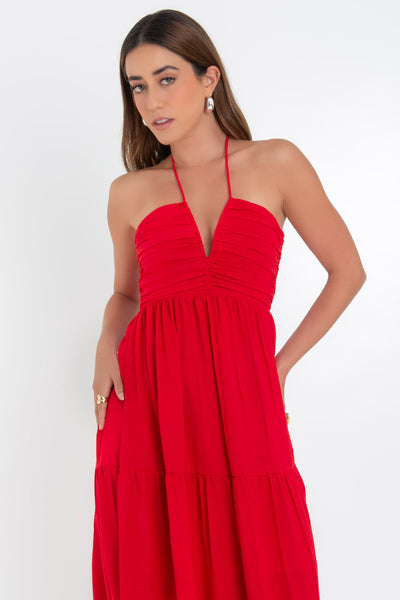 Maxi vestido de escote v con detalle de plisados en talle, cuello halter, tirantes con nudo amarrable posterior y capas de olanes en bajo. Cierre posterior con cremallera oculta.