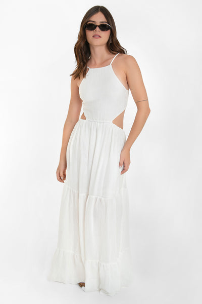 Maxi vestido de cuello halter con tirantes delgados ajustables, corte en a, bajo con capas de olanes, cut out en costados y espalda. Detalle de rib elástico en cintura y cierre posterior con lazo amarrable.
