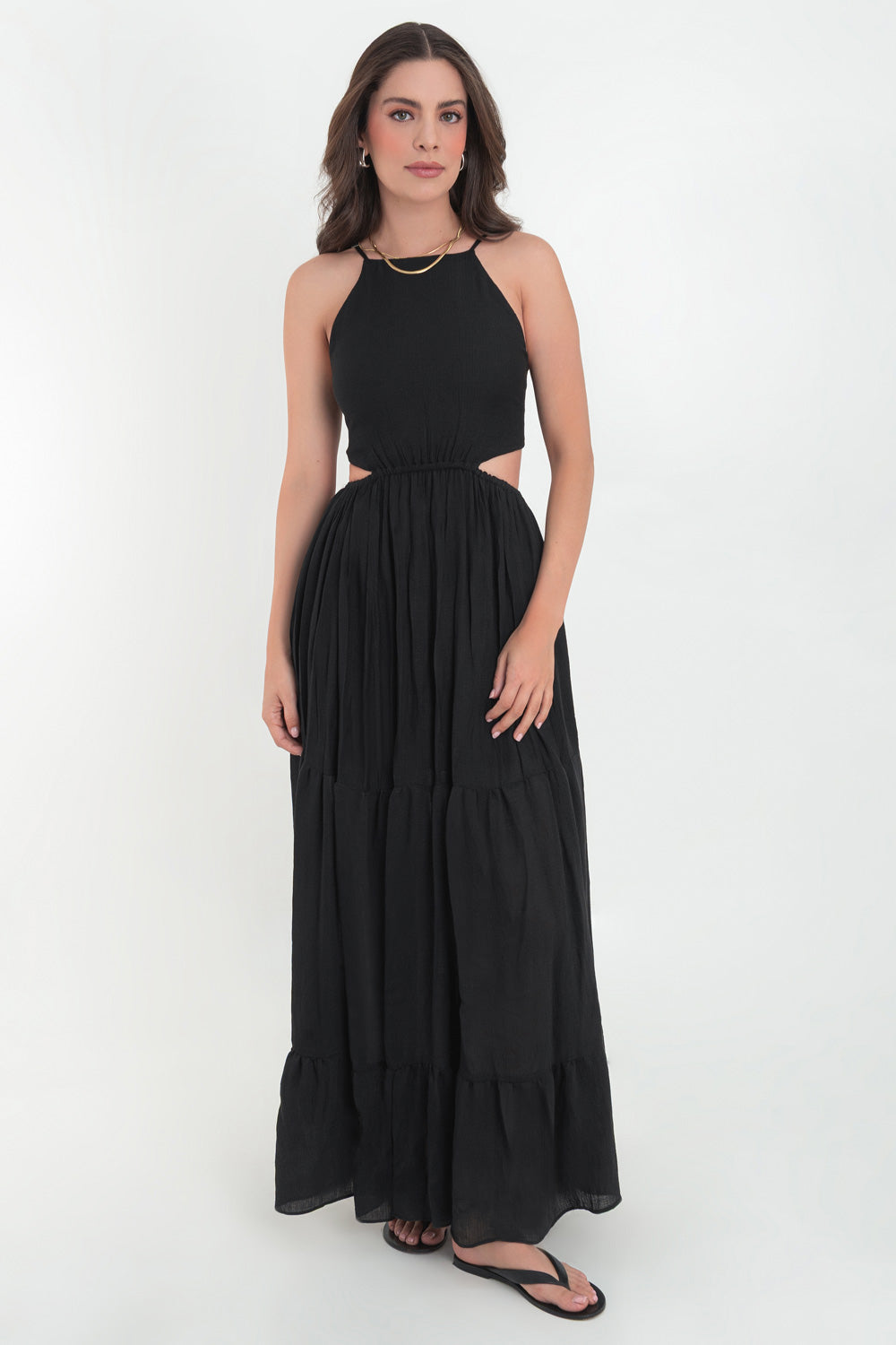 Maxi vestido de cuello halter con tirantes delgados ajustables, corte en a, bajo con capas de olanes, cut out en costados y espalda. Detalle de rib elástico en cintura y cierre posterior con lazo amarrable.