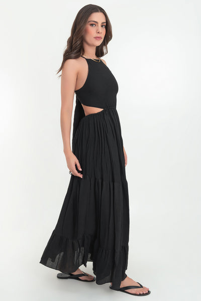 Maxi vestido de cuello halter con tirantes delgados ajustables, corte en a, bajo con capas de olanes, cut out en costados y espalda. Detalle de rib elástico en cintura y cierre posterior con lazo amarrable.
