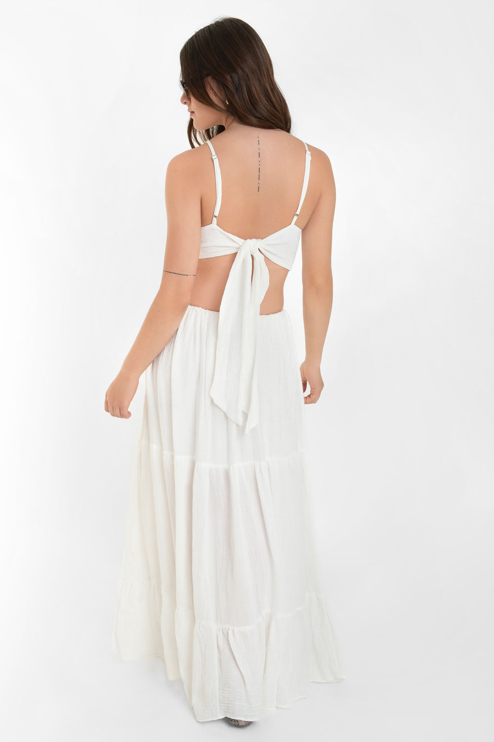 Maxi vestido de cuello halter con tirantes delgados ajustables, corte en a, bajo con capas de olanes, cut out en costados y espalda. Detalle de rib elástico en cintura y cierre posterior con lazo amarrable.