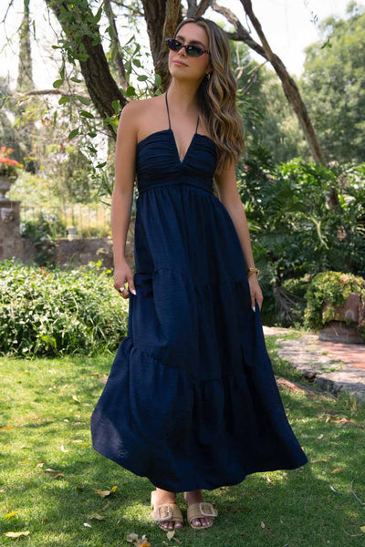 Maxi vestido escote v con detalle de plisados en talle, cuello halter, tirantes con nudo amarrable posterior y capas de olanes en bajo. Cierre posterior con cremallera oculta.