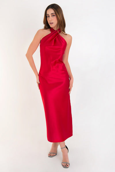 Maxi vestido satinado de fit recto, cuello halter cruzado con lazo amarrable posterior, escote en espalda y cierre posterior con cremallera oculta. Detalle de abertura lateral en bajo.