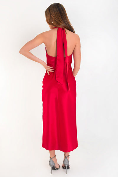 Maxi vestido satinado de fit recto, cuello halter cruzado con lazo amarrable posterior, escote en espalda y cierre posterior con cremallera oculta. Detalle de abertura lateral en bajo.