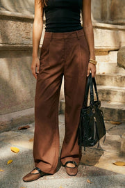 Pantalón de fit wide leg, pinzas frontales, cintura alta con pretina y trabillas, bolsillos delanteros y vivos decorativos traseros. Cierre frontal con broche y cremallera ocultos.