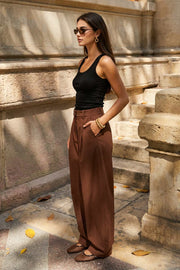 Pantalón de fit wide leg, pinzas frontales, cintura alta con pretina y trabillas, bolsillos delanteros y vivos decorativos traseros. Cierre frontal con broche y cremallera ocultos.