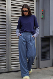 Pantalón de fit palazzo, cintura alta con trabillas, pinzas frontales, bolsillos delanteros y vivos decorativos posteriores, raya frontal y posterior. Cierre frontal con broche y cremallera ocultos.