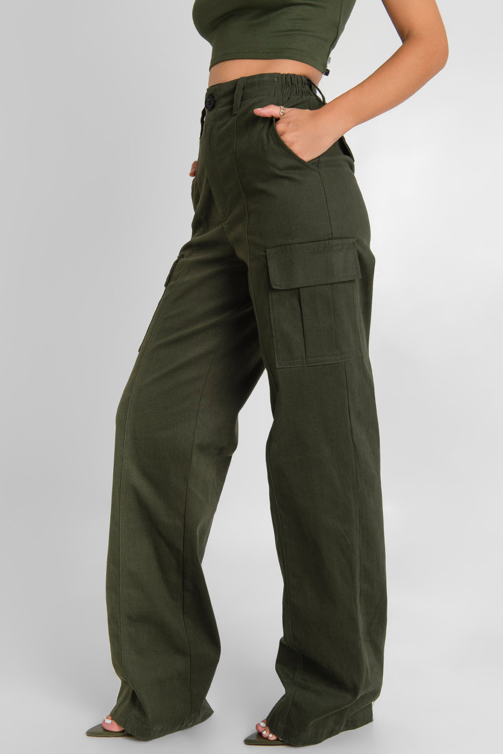 Pantalón cargo de fit wide leg, cintura alta con pretina y trabillas, bolsillos delanteros y laterales cargo con cartera, bolsillos decorativos posteriores con cartera, pretina elástica posterior y cierre frontal con botón y cremallera oculta. Detalle de raya frontal.