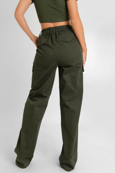 Pantalón cargo de fit wide leg, cintura alta con pretina y trabillas, bolsillos delanteros y laterales cargo con cartera, bolsillos decorativos posteriores con cartera, pretina elástica posterior y cierre frontal con botón y cremallera oculta. Detalle de raya frontal.