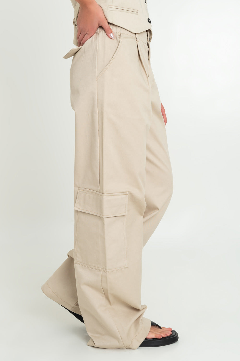 Pantalón de fit wide leg, pinzas frontales, bolsillos delanteros, laterales cargo y traseros decorativos con cartera. Cintura alta con pretina elástica posterior y trabillas, cierre frontal con botón y cremallera oculta.