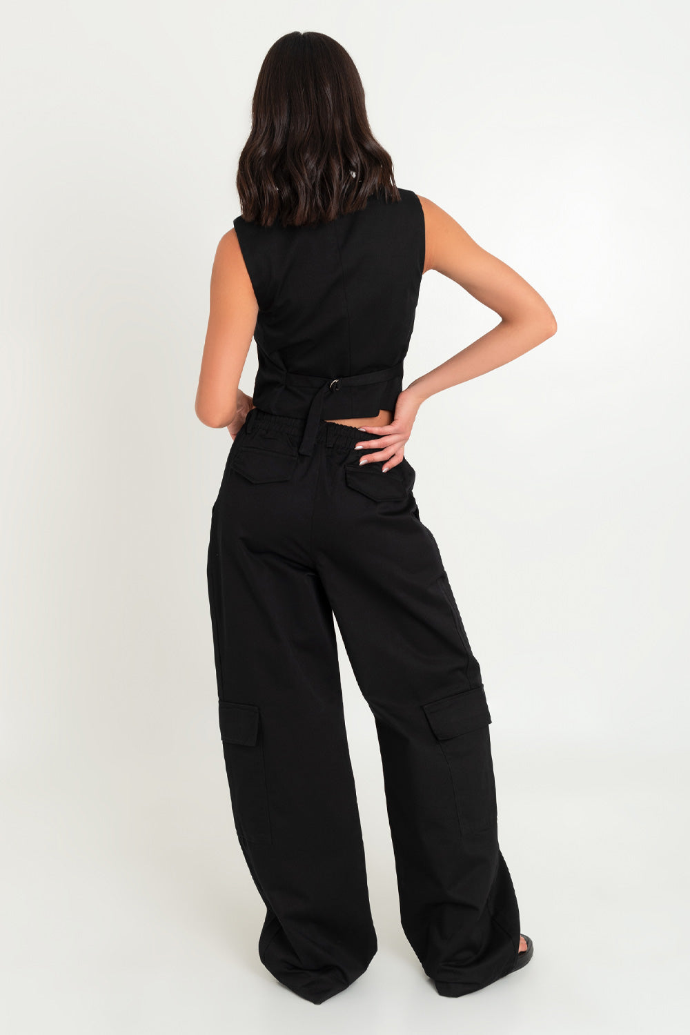 Pantalón de fit wide leg, pinzas frontales, bolsillos delanteros, laterales cargo y traseros decorativos con cartera. Cintura alta con pretina elástica posterior y trabillas, cierre frontal con botón y cremallera oculta.