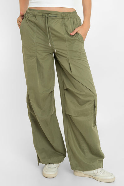 Pantalón cargo parachute de cintura media, pretina elástica con jareta frontal ajustable, fit amplio, bolsillos delanteros, laterales cargo con cartera y traseros con vivos. Detalle costuras decorativas centrales y bajo con jaretas elásticas ajustables.