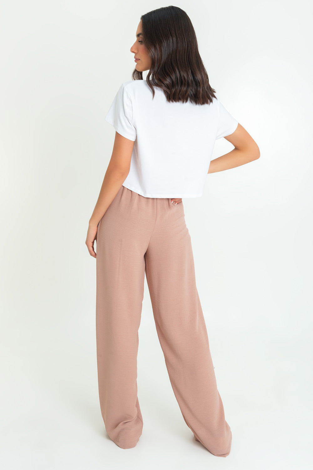 Pantalón de fit palazzo con pierna amplia, pinzas frontales, bolsillos delanteros, cintura alta de pretina con trabillas frontales y elástico posterior.