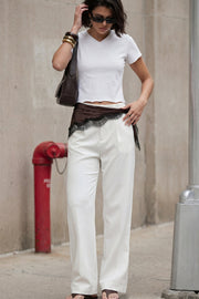 Pantalón de fit wide leg, pinzas frontales, bolsillos delanteros, cintura alta con pretina y trabillas. Detalle de vivo decorativo posterior, cierre con botón y cremallera oculta.