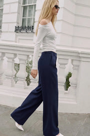 Pantalón de fit wide leg, pinzas frontales, bolsillos delanteros, cintura alta con pretina y trabillas. Detalle de vivo decorativo posterior, cierre con botón y cremallera oculta.