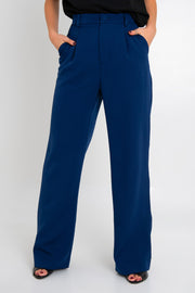 Pantalón de fit wide leg, pinzas frontales, bolsillos delanteros, cintura alta con pretina y trabillas. Detalle de vivo decorativo posterior, cierre con botón y cremallera oculta.