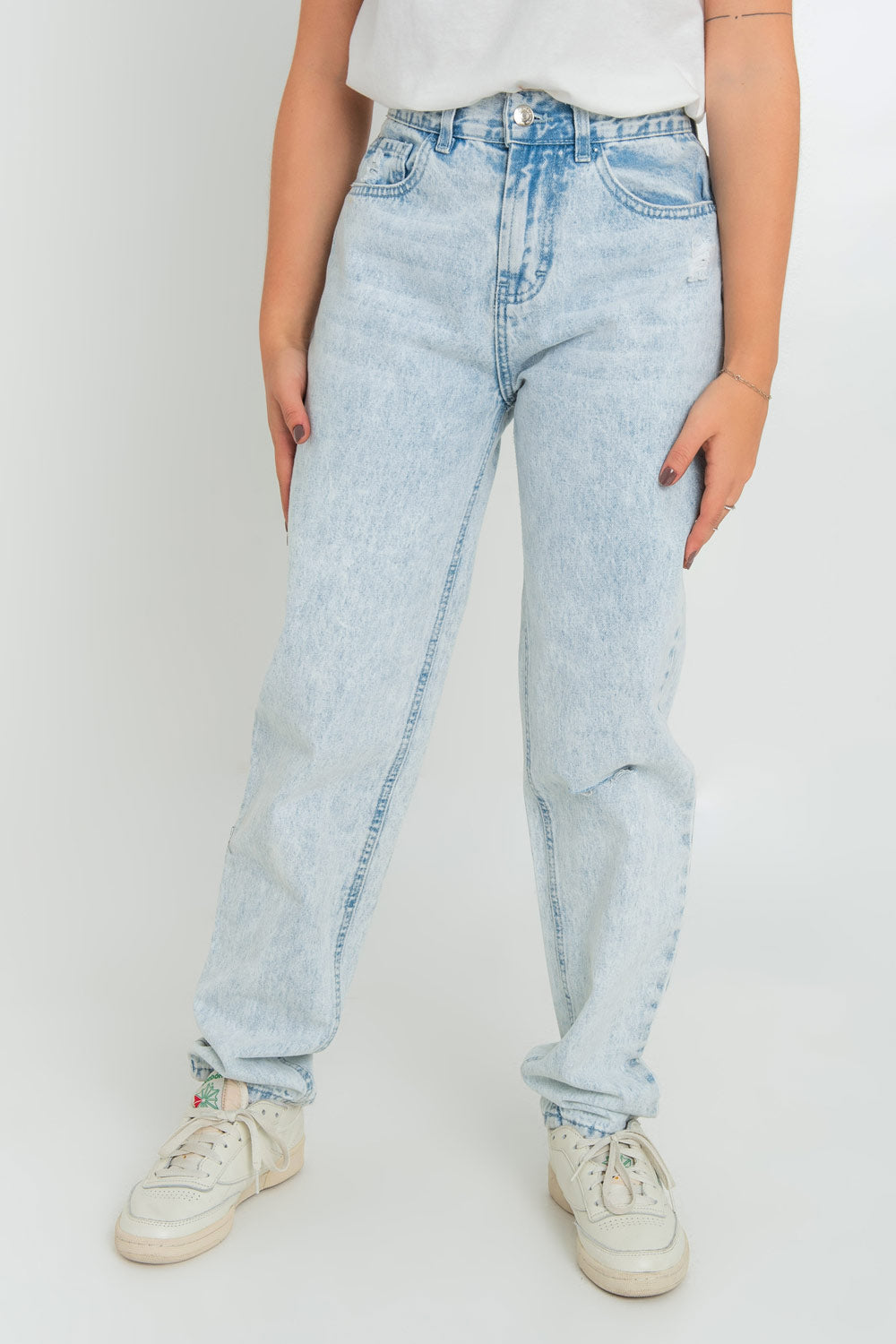 Pantalón de denim de mom fit, cintura alta con pretina, trabillas, bolsillos delanteros y traseros de parche. Cierre frontal con botón y cremallera oculta.