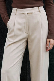 Pantalón de fit recto, cintura alta con pretina y trabillas, bolsillos delanteros, vivo decorativo posterior y pinzas frontales. Cierre con broche y cremallera ocultos.