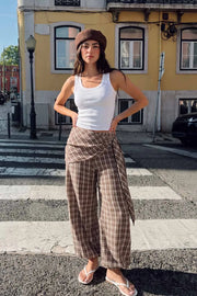 Pantalón fluido de fit palazzo, estampado cuadros, cintura media con pretina elástica, plisados en costado y detalle de pareo decorativo con nudo lateral.