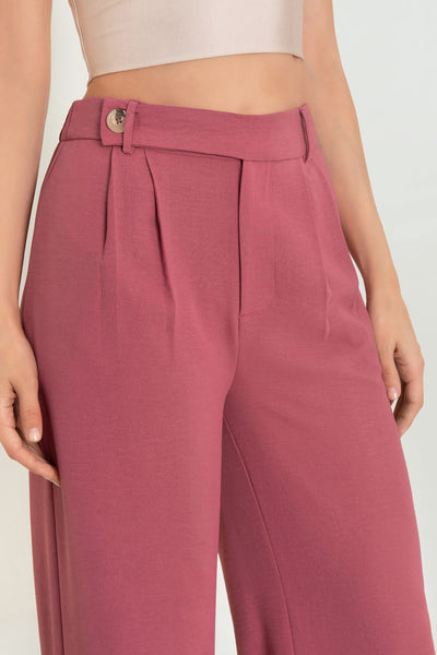 Pantalón de fit culotte, cintura alta con pretina elástica posterior y trabillas, pinzas frontales, bolsillos delanteros y vivos decorativos posteriores. Cierre frontal con cremallera oculta y trabilla con botón en contraste.