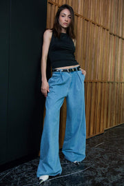 Pantalón de denim fit palazzo, cintura baja con pretina y trabillas, pinzas frontales, bolsillos delanteros, cierre frontal con botón y cremallera oculta.
