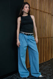 Pantalón de denim fit palazzo, cintura baja con pretina y trabillas, pinzas frontales, bolsillos delanteros, cierre frontal con botón y cremallera oculta.