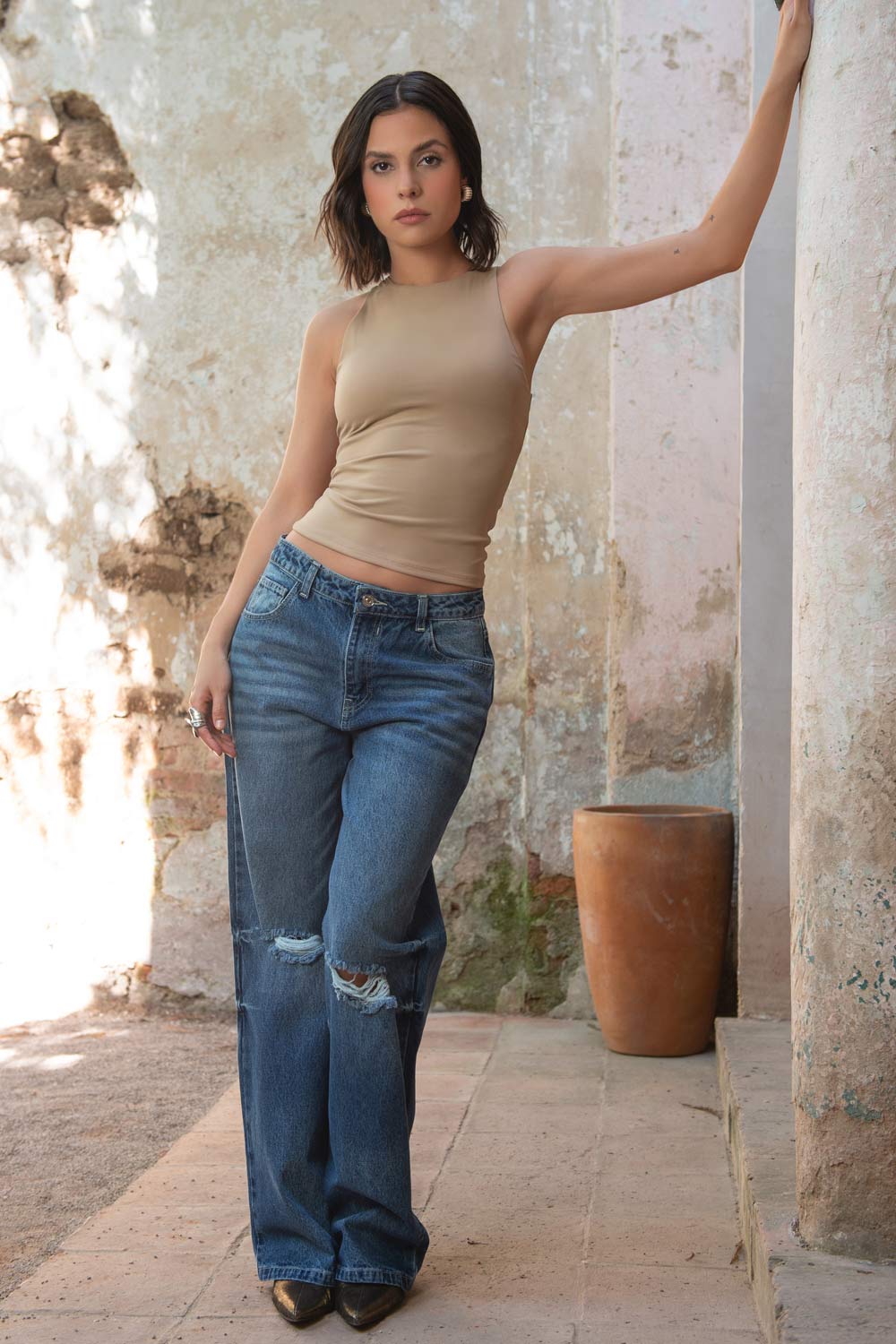 Pantalón de denim, fit wide leg, con rotos en rodillas, tiro medio con pretina y trabillas, bolsillos delanteros y traseros de parche. Cierre con botón y cremallera oculta.