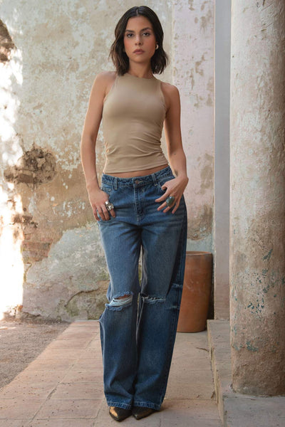 Pantalón de denim, fit wide leg, con rotos en rodillas, tiro medio con pretina y trabillas, bolsillos delanteros y traseros de parche. Cierre con botón y cremallera oculta.