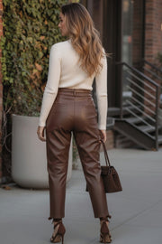Pantalón de efecto piel, fit recto, cintura alta con pretina y trabillas, pinzas frontales, bolsillos delanteos y vivos decorativos posteriores.