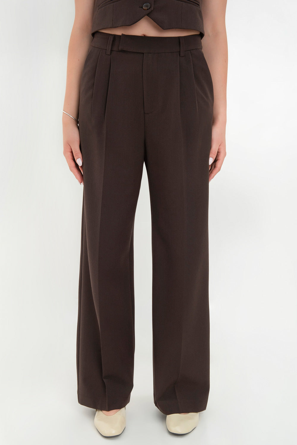 Pantalón de fit recto, pinzas frontales con raya, cintura media con pretina elástica posterior y trabillas, bolsillos delanteros y vivo decorativo posterior. Cierre frontal con broche y cremallera ocultos.