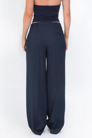 Pantalón de fit wide leg, cintura baja con pretina y trabillas, vivo decorativo posterior y detalle de raya frontal. Cierre frontal con botón y cremallera oculta.