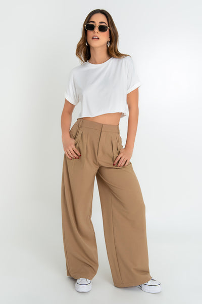 Pantalón de fit wide leg, cintura alta con pretina y trabillas, bolsillos delanteros y pinzas frontales. Cierre frontal con broche y cremallera oculta.