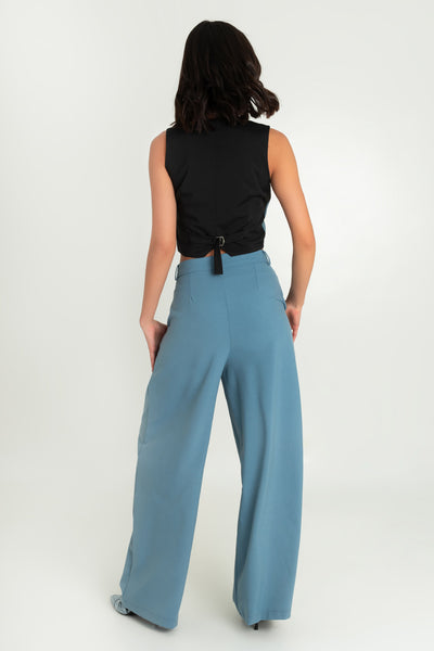 Pantalón de fit wide leg, cintura alta con pretina y trabillas, bolsillos delanteros y pinzas frontales. Cierre frontal con broche y cremallera oculta.