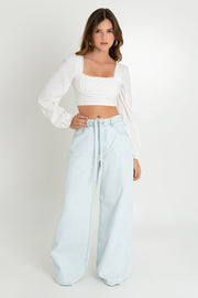 Pantalón de denim wide leg fit, bolsillos delanteros y traseros de parche, cintura alta con pretina, trabillas y cinturón amarrable del mismo tejido. Cierre frontal con botón y cremallera oculta.