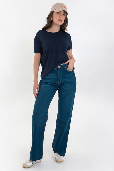 Pantalón light denim de pierna amplia, cintura alta con pretina, trabillas, bolsillos delanteros y traseros de parche. Cierre frontal con botón y cremallera oculta. Detalle de rotos en bajo.