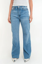 Pantalón light denim de pierna amplia, cintura alta con pretina, trabillas, bolsillos delanteros y traseros de parche. Cierre frontal con botón y cremallera oculta. Detalle de rotos en bajo.