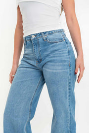 Pantalón light denim de pierna amplia, cintura alta con pretina, trabillas, bolsillos delanteros y traseros de parche. Cierre frontal con botón y cremallera oculta. Detalle de rotos en bajo.