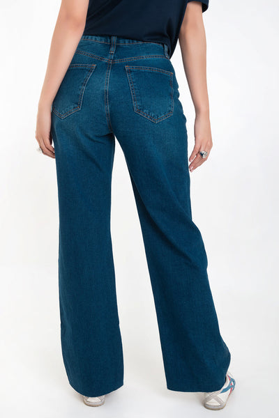Pantalón light denim de pierna amplia, cintura alta con pretina, trabillas, bolsillos delanteros y traseros de parche. Cierre frontal con botón y cremallera oculta. Detalle de rotos en bajo.