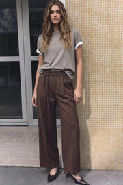Pantalón de fit wide leg, cintura alta con pretina, trabillas y doble lazo amarrable, pinzas frontales y bolsillos delanteros. Cierre frontal con broche y cremallera ocultos.